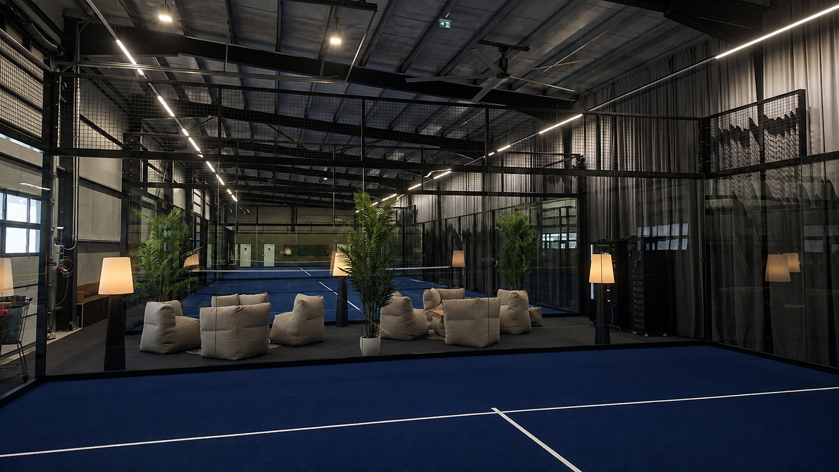 Indoor-Padel-Court mit blauem Belag und gemütlichem Lounge-Bereich in Villach